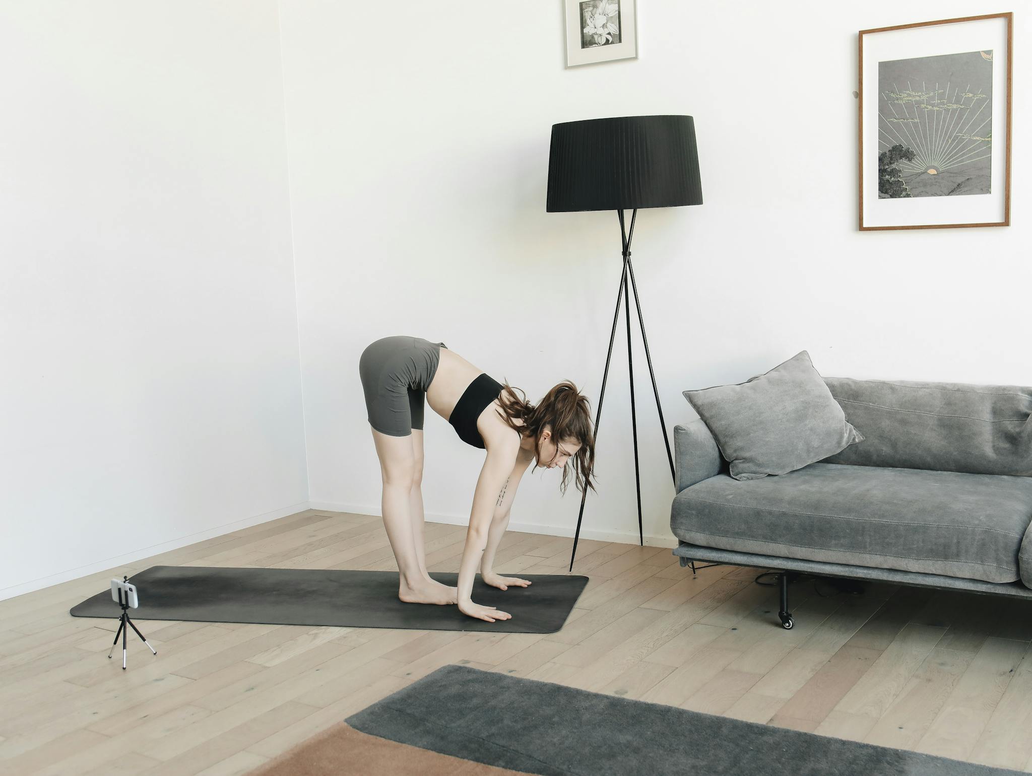 A woman performing yoga indoors in a minimalist living room setting, captured in a yoga pose.